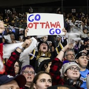 Une jeune fille avec une pancarte «Go Ottawa Go» pendant un match de hockey féminin.