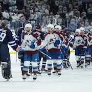 Les joueurs de deux équipes de hockey se félicitent après un match.