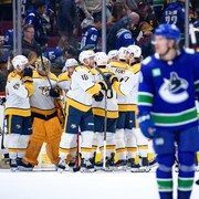 Les joueurs d'une équipe de hockey sont regroupés autour de leur gardien et se réjouissent.