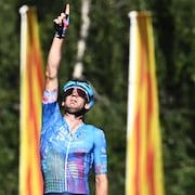 Le cycliste pointe son index droit vers le ciel.