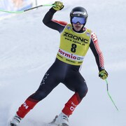 Un skieur casqué lève le bras droit dans l'aire d'arrivée, et semble satisfait. 