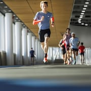 Un jeune homme court sur une piste intérieure. 