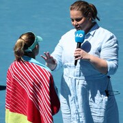 Une jeune femme tient un micro et parle à une joueuse de tennis de dos.