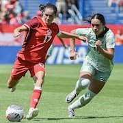 Une joueuse de soccer contrôle le ballon devant une rivale.