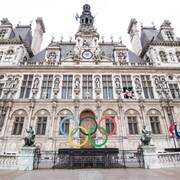 Les anneaux olympiques devant un bâtiment patrimonial.