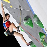 Elle gravit un mur d'escalade.