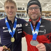 Deux patineurs de vitesse prennent la pose avec leur médaille.