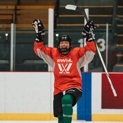 Une joueuse de hockey lève les bras au ciel. 