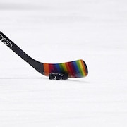 Un bâton de hockey se trouve sur la patinoire avec du ruban multicolore.