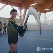 Une joueuse de dek hockey tient un bâton de hockey.