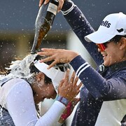 Lilia Vu (à gauche, en blanc) se fait asperger de champagne après avoir réussi son roulé au 18e trou pour gagner l'Omnium britannique de golf.