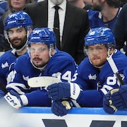 Des joueurs de hockey en bleu à leur banc. 