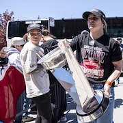 Entour&eacute;e de partisans, elle tient le troph&eacute;e &agrave; deux mains.
