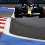 Max Verstappen, dans sa Red Bull, s'apprête à attaquer un virage, les vibreurs à la droite de sa voiture. 