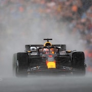Max Verstappen au volant de sa Red Bull négocie le tracé de Zandvoort, alors qu'un nuage d'eau se soulève derrière sa voiture. 