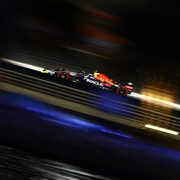 Une voiture, de profil, roule de nuit sur un circuit de F1.