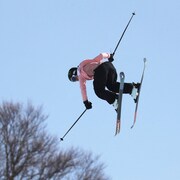 Une skieuse acrobatique effectue une manœuvre dans les airs.