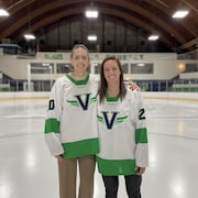 Deux femmes avec un chandail blanc et vert sur une patinoire