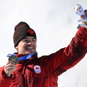Le poing levé, il tient sa médaille d'or, tout sourire.