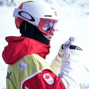 Un skieur casqué de profil regarde au loin, sur sa droite.