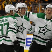 Trois joueurs de hockey se félicitent sur une patinoire. 