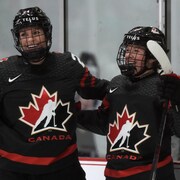 Deux joueuses de hockey sourient après avoir inscrit un but.