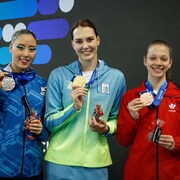 Les trois nageuses montrent leurs médailles.