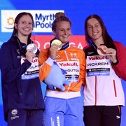 Les trois nageuses posent avec les médailles sur le podium. 