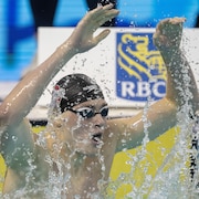 Tristan Jankovics célèbre dans l'eau en levant les bras.