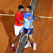 Deux joueurs de tennis se font l'accolade après un match.