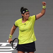 Une joueuse de tennis lève le poing gauche au ciel après une victoire.
