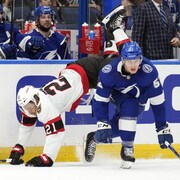 Un joueur de hockey tombe sur la glace après en avoir heurté un autre.