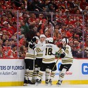 Quatre joueurs des Bruins célèbrent un but devant une foule de partisans déçus.