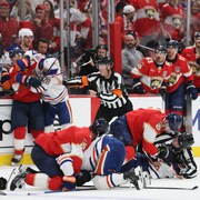 Des joueurs des deux équipes se retiennent sur la patinoire.