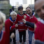 Trois partisans du Canadien v&ecirc;tus de chandails rouges de l'&eacute;quipe brandissent leurs poings en signe de support &agrave; l'.quipe.