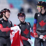 L'équipe canadienne médaillée d'or avec Valérie Maltais, Isabelle Weidemann et Ivanie Blondin célèbre pendant la cérémonie de la finale de la poursuite par équipe féminine.