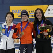 Trois patineuses prennent la pose sur un podium.