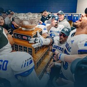 Des joueurs autour d'un trophée célèbrent leur victoire.