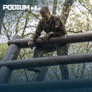 Deux militaires tentent de franchir des barrières en bois dans une forêt.