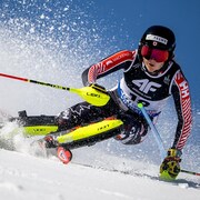 Gros plan d'une skieuse accroupie dans un virage.