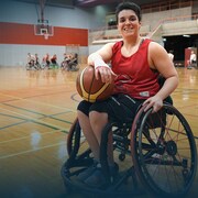 Une joueuse de basketball en fauteuil roulant sourit sur un terrain