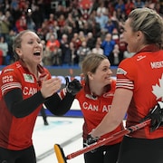 Des joueuses de curling célèbrent leur victoire devant la foule. 