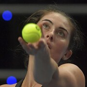 Une joueuse de tennis lève les yeux au ciel au moment de lancer la balle pour effectuer son service.