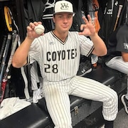Un joueur de baseball montre une balle dans un vestiaire.