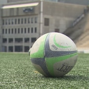 Deux ballons de rugby sur le terrain synthétique du stade Percival-Molson, à Montréal.