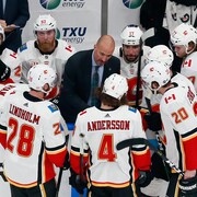 L'entraîneur-adjoint Ryan Huska donne des instructions aux joueurs sur le banc des Flames, lors d'un match le 11 août 2020.