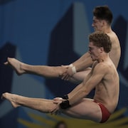 Deux plongeurs en position carpée, dans les airs.