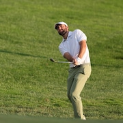 Un golfeur suit la balle des yeux après avoir frappé un coup.