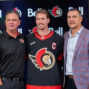 Un joueur de hockey avec un nouveau chandail de capitaine prend la pose pour les cam&eacute;ras.