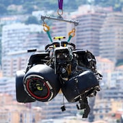 La voiture Red Bull de Sergio Pérez, lourdement endommagée, est soulevée par une grue mécanique. 